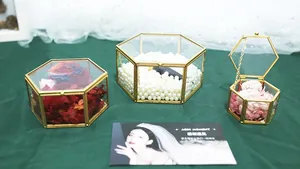 Detailed view of hexagonal glass jewelry boxes with gold metal frames and floral decor