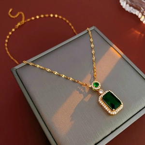 Close-up of a gold emerald necklace with square pendant and pavé diamonds on jewelry box