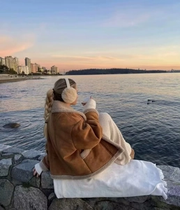 Nahaufnahme einer braunen Lammfelljacke mit beigen Ohrenschützern in einer Sonnenuntergangsszene