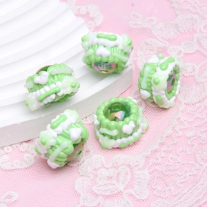 Detail of green hand-painted DIY beads with cream decoration and colorful crystals