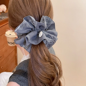 Detailed view of grey paisley scrunchie with button on a soft wavy ponytail