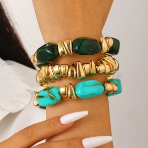 Detailed close-up of layered beaded bracelets with metallic gold and green resin beads