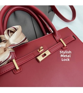 Détail d'un sac à main en cuir rouge avec boucle en métal doré et poignée en foulard