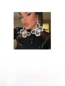 Detailed view of oversized butterfly drop earrings with sparkling rhinestones in gold