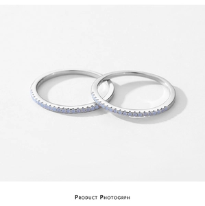 Detail of two minimalist S925 silver rings with inlaid light blue crystals on white background