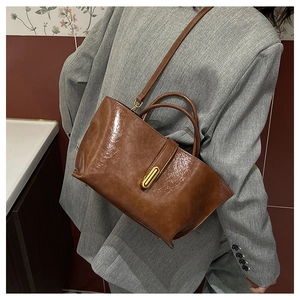 Detailed close-up of vintage brown tote bag featuring glossy leather and golden metal clasp