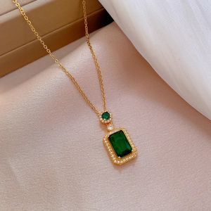 Macro shot of titanium steel necklace featuring emerald green stone and small pavé diamonds