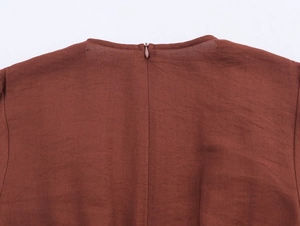 Close-up of rust brown dress back showing crepe texture fabric and hidden zipper detail