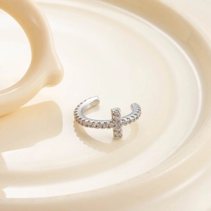 Manchette d'oreille en argent avec croix et zircons sur un plateau en céramique crème