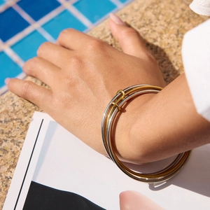 Three-band interlocking stainless steel bracelet in gold and silver by the pool