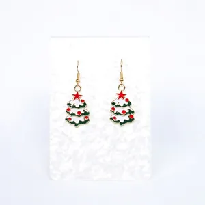 Festive Christmas tree dangle earrings with green enamel and red star on marble stand