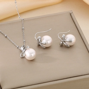 Macro shot of pearl necklace and bow earrings set on elegant yellow satin background