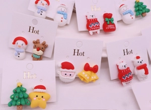 Close-up of Christmas clip-on earrings featuring resin Santa Claus and reindeer designs