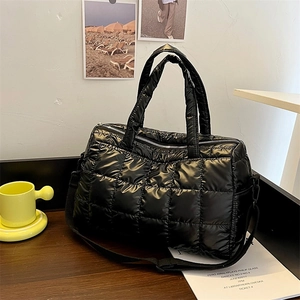 Detailed view of black quilted puffer tote bag on wooden desk with stylish glossy finish