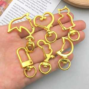 Sechsteiliges Set goldener Karabinerhaken in Delfin-, Mond- und Herzform in der Hand