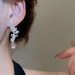 Close-up of silver flower hollow clip-on earrings with crystals on woman's ear