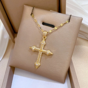 Detailed view of luxury gold cross pendant necklace with micro-pave zircons in a jewelry box