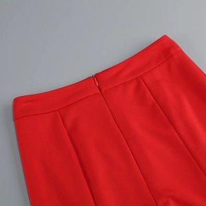 Détail du pantalon rouge à taille haute avec fermeture éclair invisible et tissu texturé