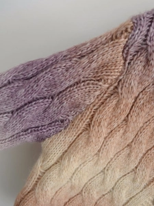 Macro shot of thick cable knit texture with soft purple to beige color gradient