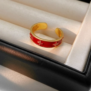 Macro detail of 18k gold flower ring with red enamel and star-shaped crystals