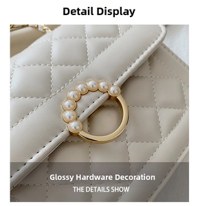 Close-up of golden round buckle with pearl embellishment on white quilted bag