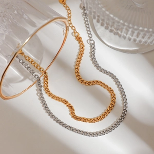 Dual-layer mixed gold and silver Cuban link chain anklet on a glass stand