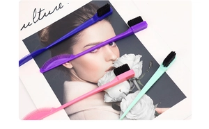 Close-up of four colorful double-sided eyebrow brushes and combs on a stylish magazine