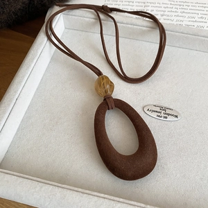 Detail of vintage flocked resin necklace with amber beads on a cream jewelry tray