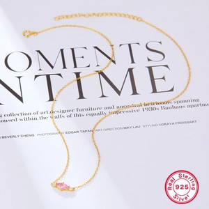 Macro detail of S925 sterling silver gold-plated chain with marquise cut pink zircon pendant