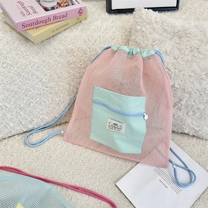 Détail d'un sac à dos en maille rose avec poche verte et décorations de perles