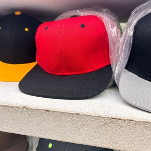 Detail of red and black hip-hop baseball cap with flat brim on a warehouse shelf