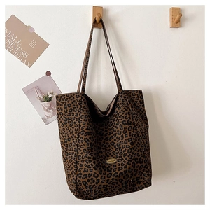 Detailed view of leopard print tote bag hanging on a wooden hook with soft natural lighting