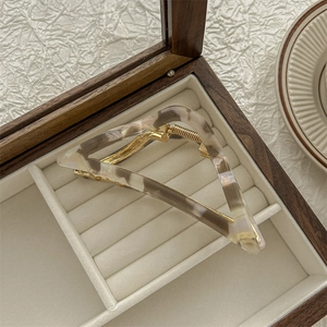 Detail van driehoekige haarclip van marmeren acetaat in een met fluweel beklede houten doos