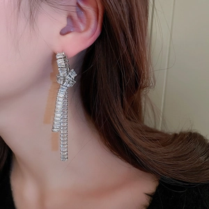 Macro shot of long silver tassel earrings with square cubic zirconia fringe on model