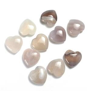 Flat lay of multiple polished 20mm heart-shaped natural crystal gemstones on white background