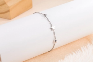Close-up of minimalist silver star pendant bracelet on a white display stand