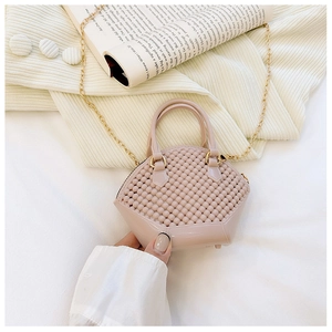 Pink mini shell jelly bag with gold chain strap and pearl handle in life-like setting