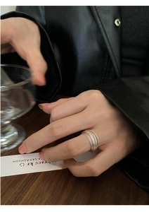 Detail view of multilayer geometric silver ring worn with a stylish black leather jacket