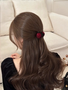 Detail of red velvet rose hair claw clip on brunette hair for a half-up hairstyle