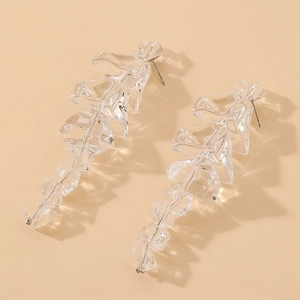 Detailed macro view of long irregular clear acrylic ice-shaped beads on silver needle earrings