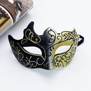 Detail of a venetian half-face masquerade mask with black and gold glitter flower patterns