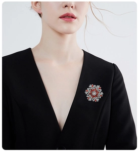 Detailed view of a silver snowflake brooch with red crystals on a black suit lapel
