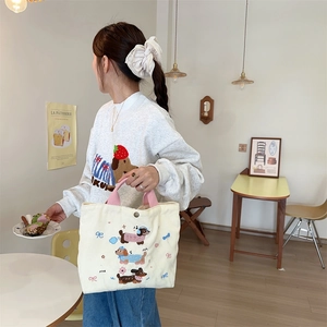 Dettaglio del ricamo bassotto e cinturino rosa sulla borsa lunch in velluto