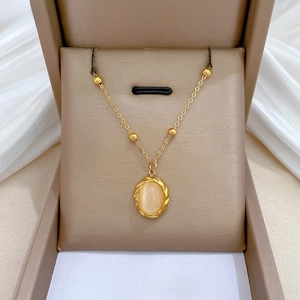 Detail of gold titanium necklace with opal pendant on elegant champagne jewelry box
