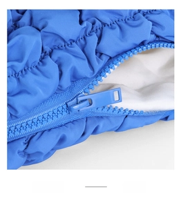 Detail of smooth blue zipper on quilted puffer fabric with soft white inner lining