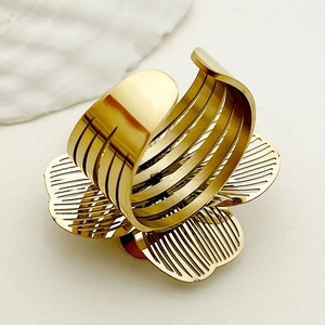 Detailed close-up of golden hollow flower ring with adjustable open band on white surface