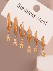 Detail view of gold stainless steel huggie earrings set with sparkling zircon astronauts