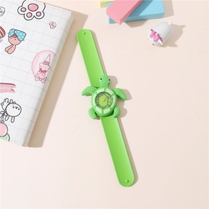 Detail of green turtle cartoon slap watch for kids on a pink desk with toy blocks