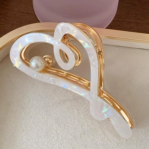 Detailed close-up of a white heart-shaped acetic acid hair claw with pearl accent
