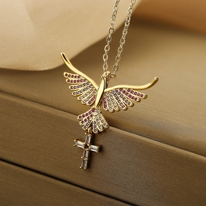 Detailed view of a gold cross pendant necklace featuring pink stones and a bird motif